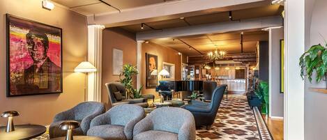 Un área de estar moderna con asientos cómodos, un piano y un bar al fondo.
