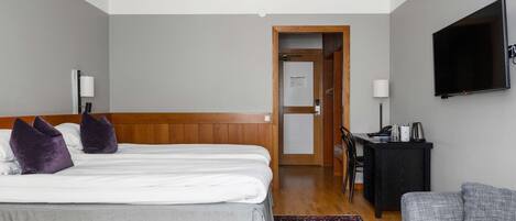 A hotel room with two beds, a desk, a television, and a sofa.