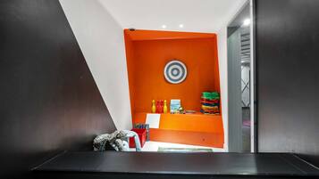 A modern room with a black desk, an orange accent wall, and a target decoration.