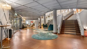 Eine großzügige Lobby mit Treppe, Rezeption und einer Sitzecke.