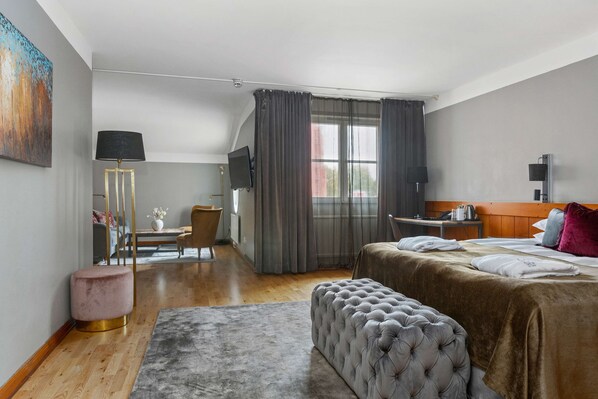 Une chambre d’hôtel avec un lit, un bureau, une chaise, une lampe et un tableau au mur.