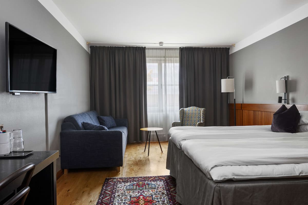 Een hotelkamer met een bed, een bank, een televisie, een tafeltje en een stoel.