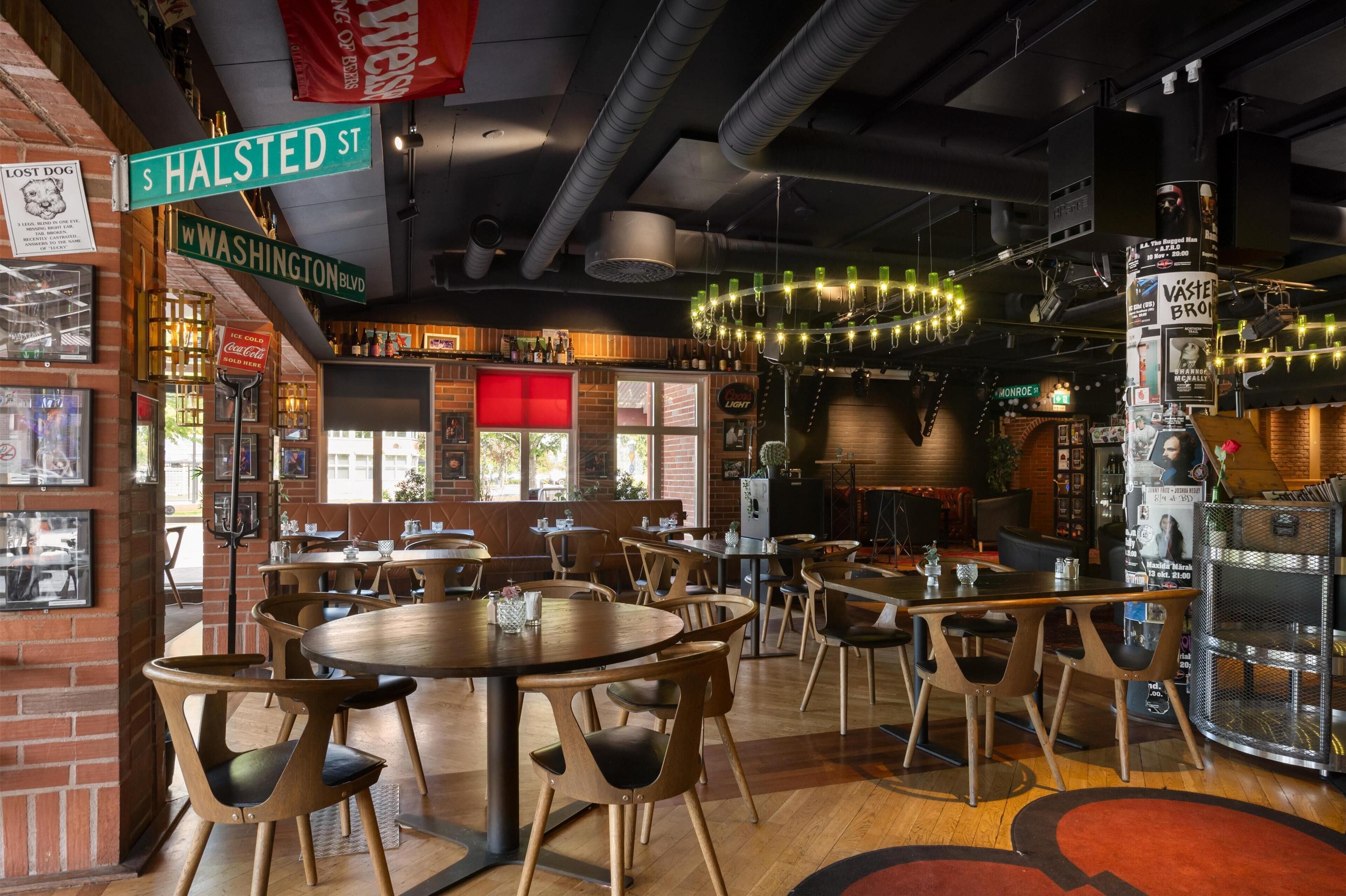 Un interno ristorante con tavoli e sedie in legno, una zona bar e un muro in mattoni.