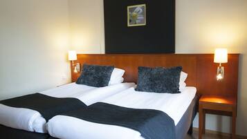A double bed with white and black bedding, two bedside tables with lamps, and a framed picture on the wall.