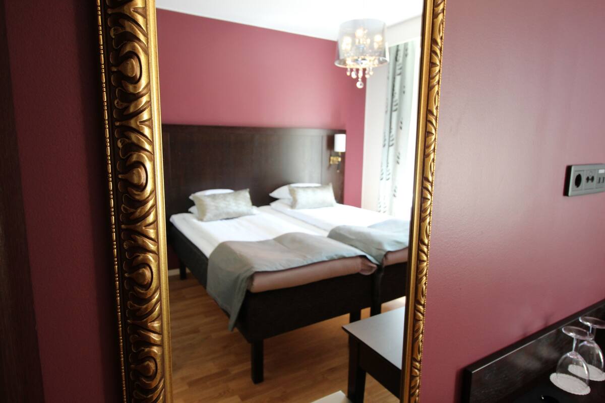 A bedroom with a bed, a nightstand, a mirror, and a chandelier.