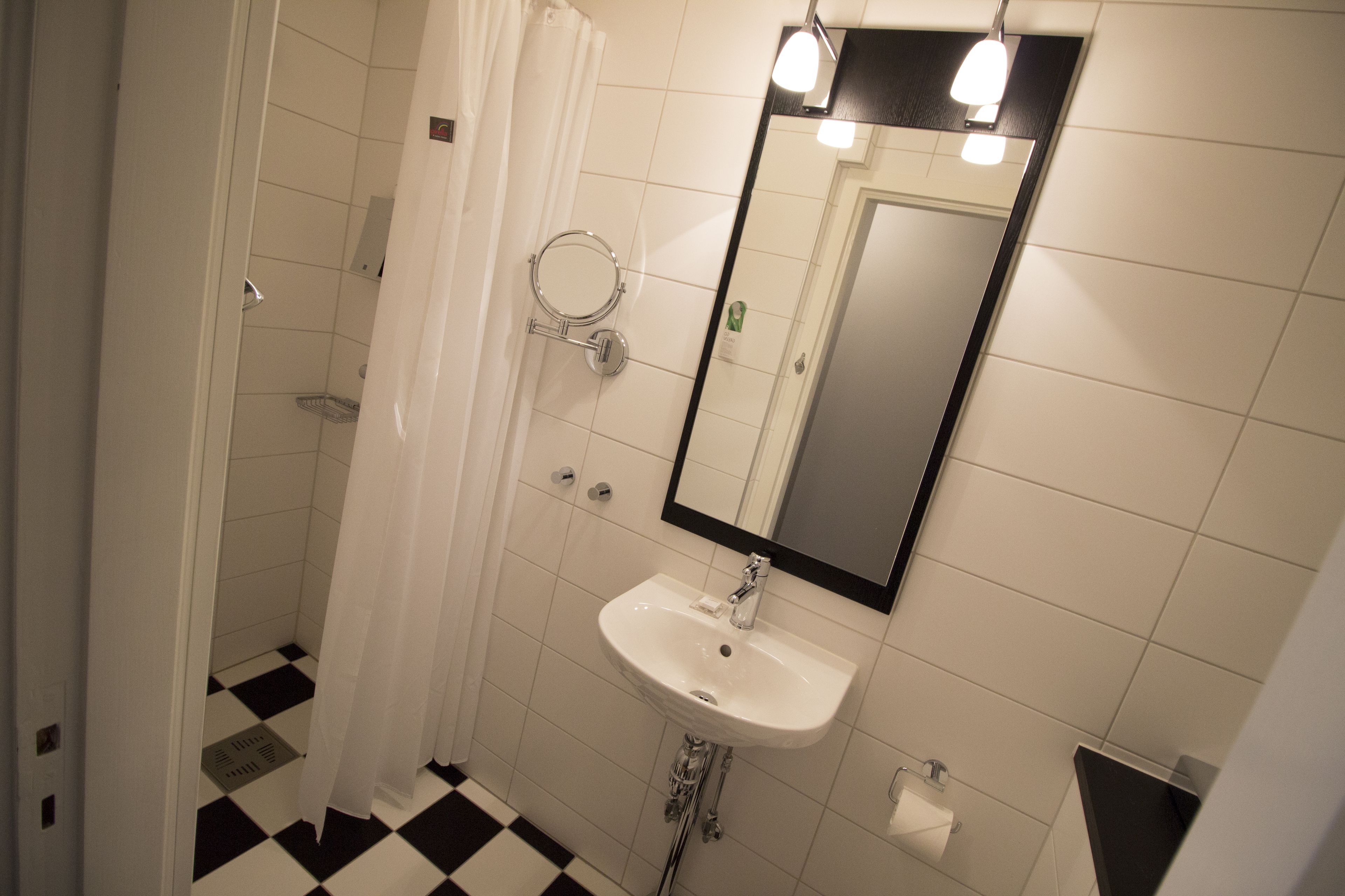 Un baño con lavamanos blanco, un espejo y una cortina de ducha.