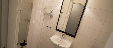 Un baño con lavamanos blanco, un espejo y una cortina de ducha.