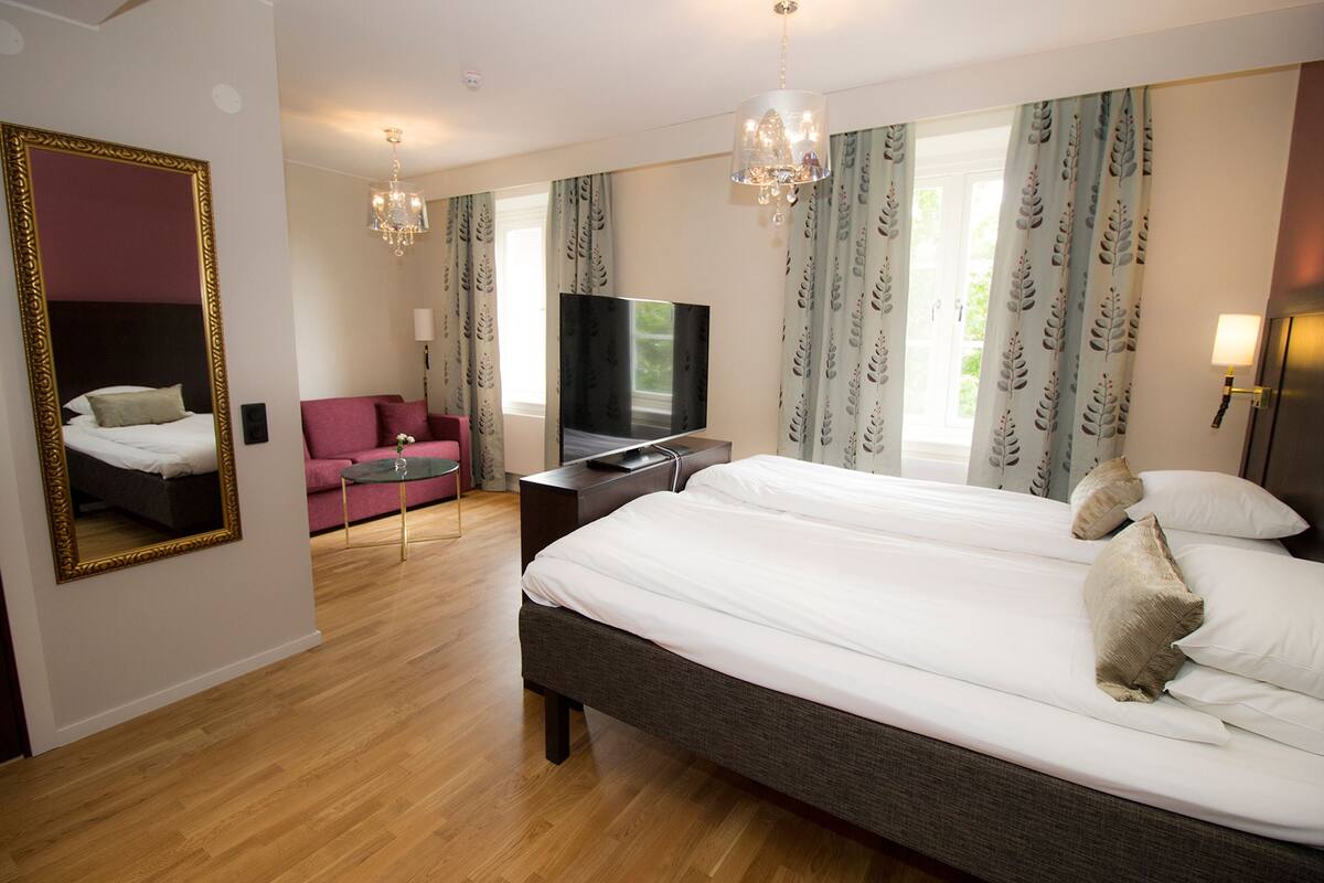 A hotel room with a large bed, a television, a desk, and a chair.
