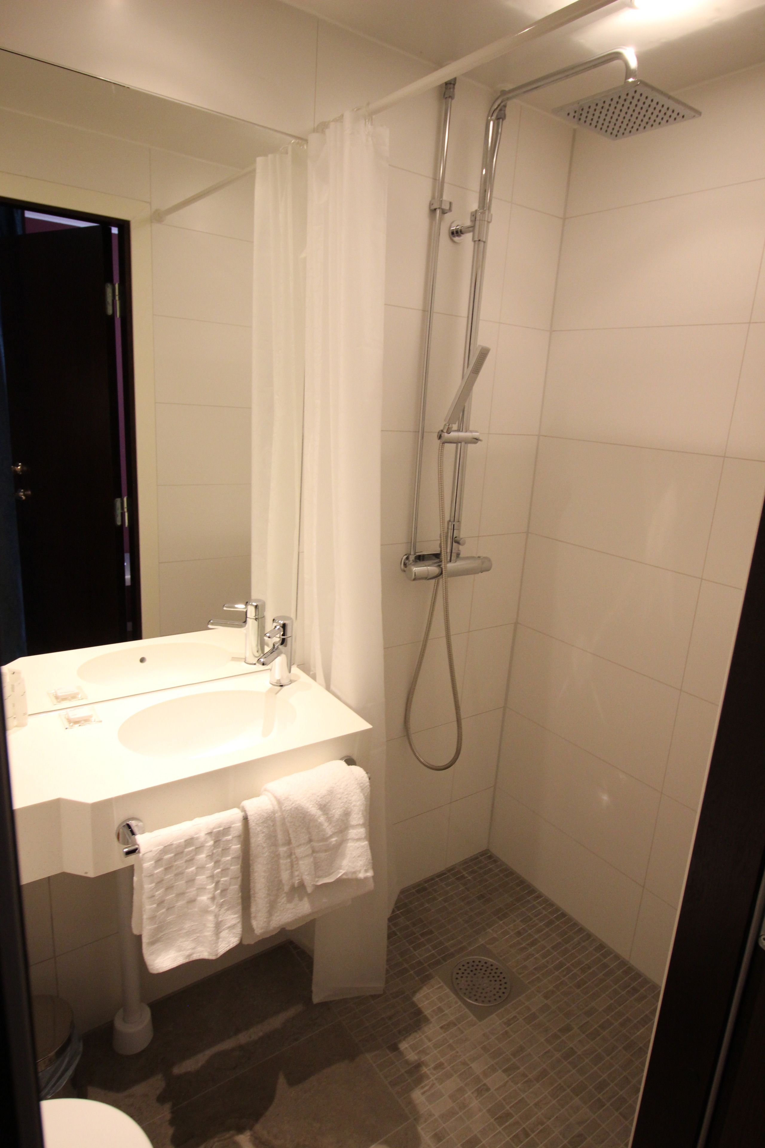A bathroom with a white sink, mirror, and shower.