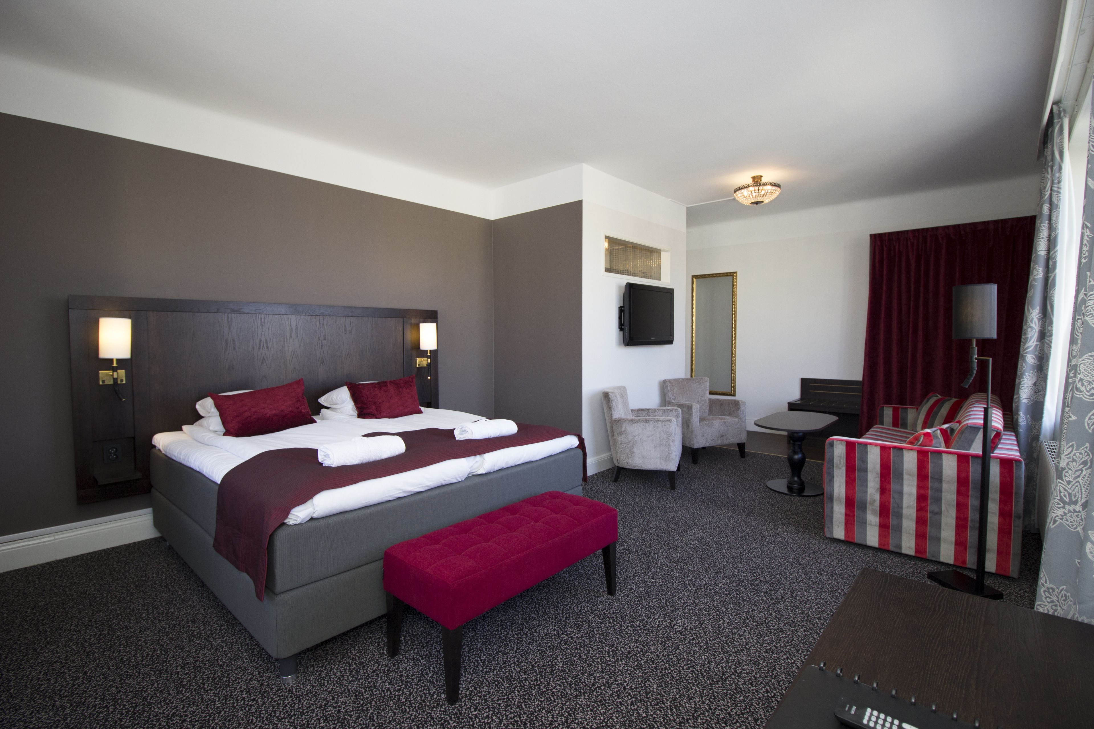 Una habitación de hotel con cama, escritorio, silla y televisión.
