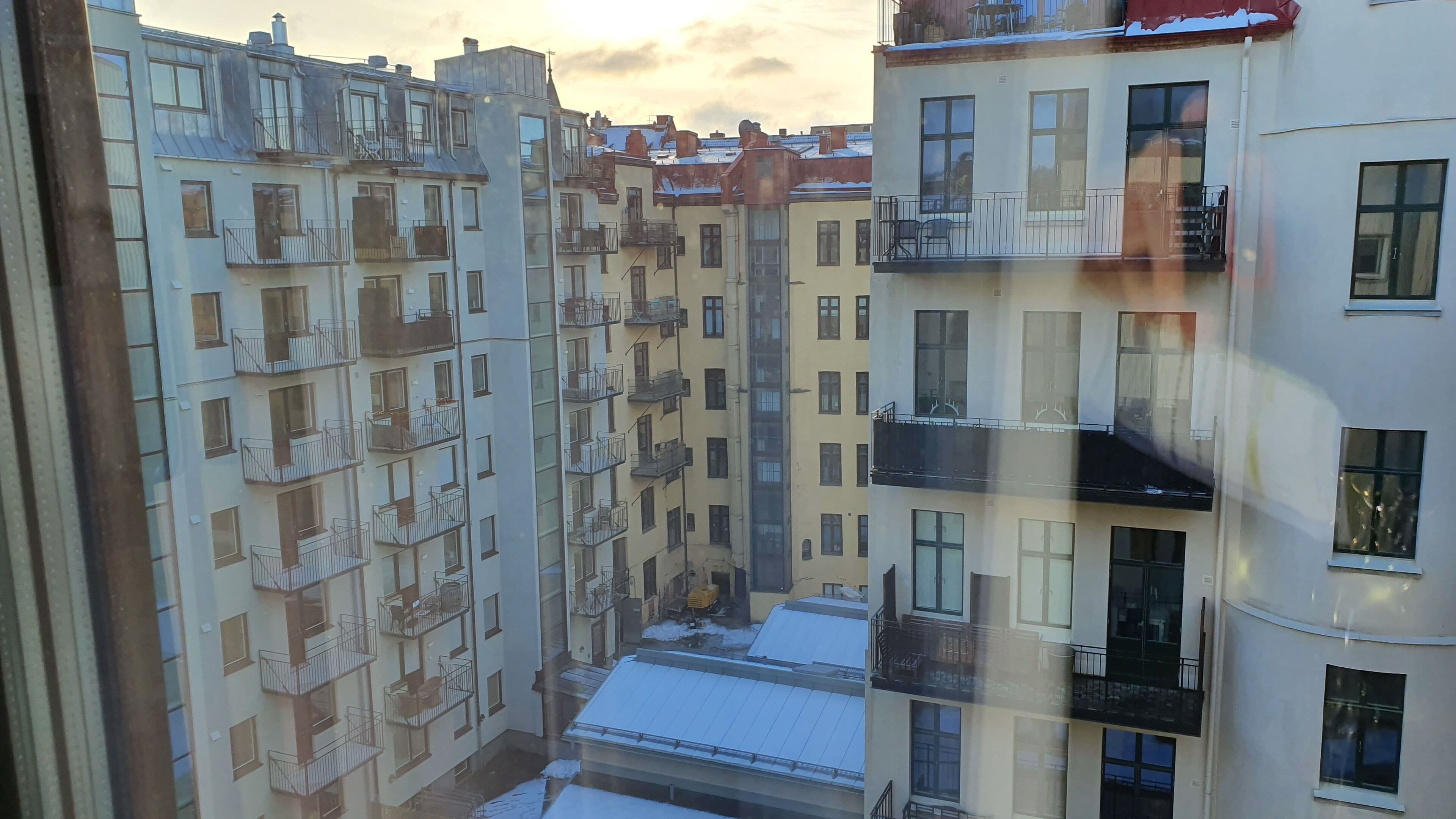 Un edificio residencial de varios pisos con balcones, un patio interior y un techo cubierto de nieve.