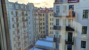 Un edificio residencial de varios pisos con balcones, un patio interior y un techo cubierto de nieve.