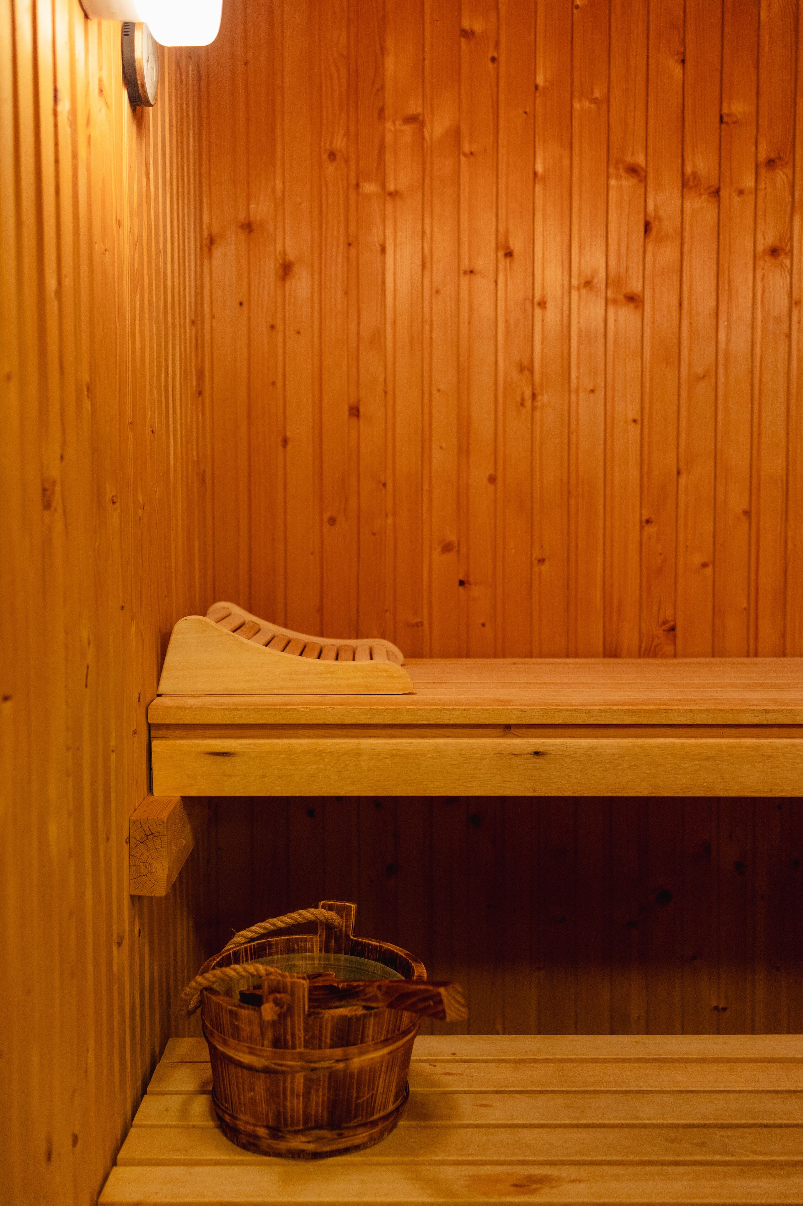 Un sauna en bois avec un banc et un panier de bois de chauffage.