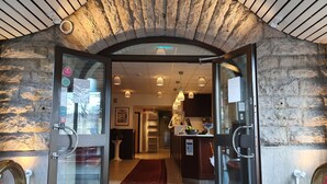 A hotel entrance with a stone facade, a red carpet, and a reception desk. - Hotel Lorensberg (Gothenburg)