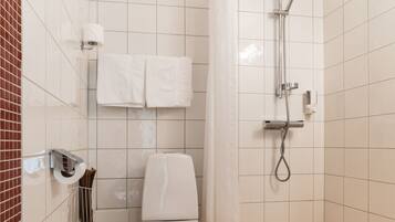 A small, tiled bathroom with a toilet, a shower, and a towel rack.