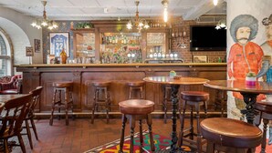 Un área de bar con taburetes de madera, barra y televisor montado en la pared.