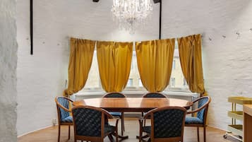 A dining room with a wooden table and chairs, yellow curtains, and a chandelier.