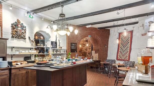 Un restaurante con pared de ladrillo, armarios de madera y una isla central con comida y bebidas.