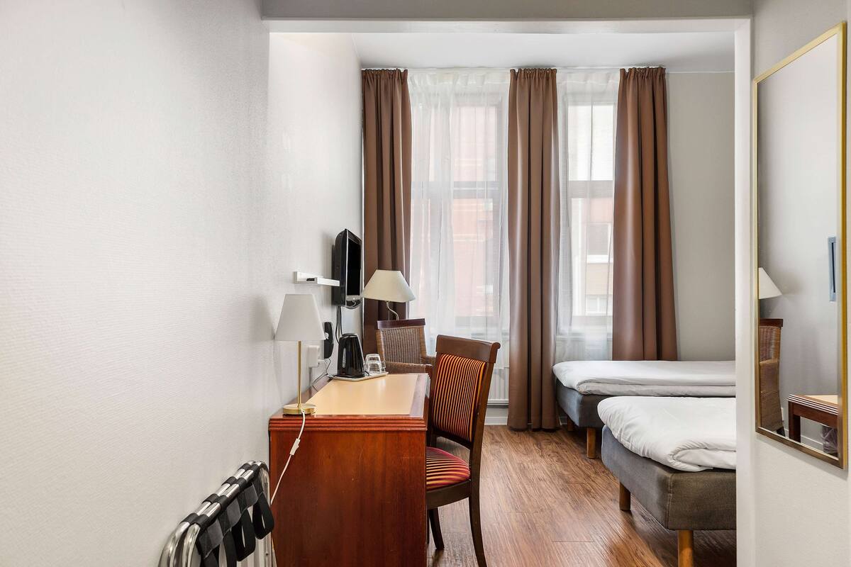 Una habitación de hotel con escritorio de madera, una silla, una cama y un televisor.