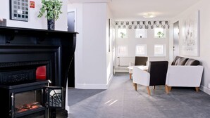 Una sala de estar moderna con chimenea, un conjunto de sofá y un marco de fotos colgado en la pared.