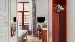 Un dormitorio con una cama, un escritorio con silla, un televisor y un armario.