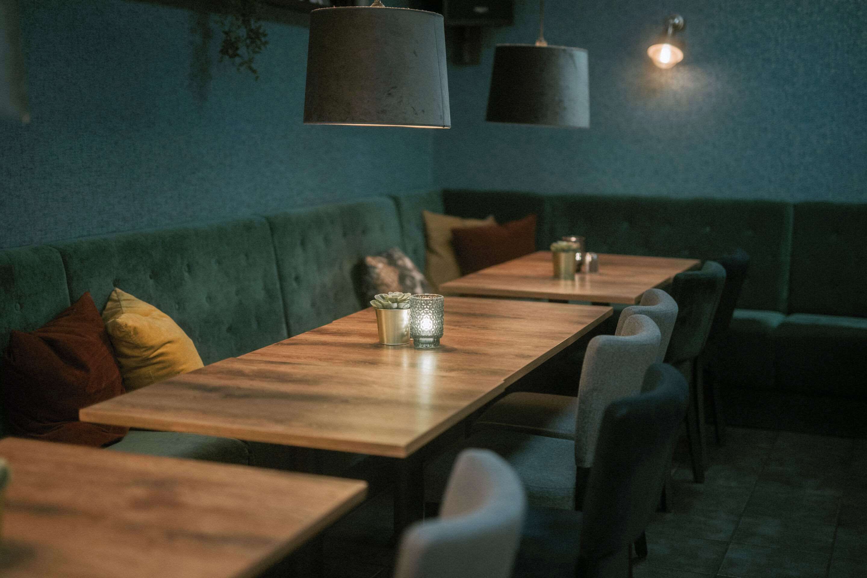 Un restaurante con una larga mesa de madera, asientos acolchados e iluminación colgante.