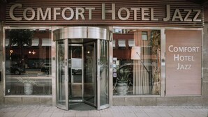 Comfort Hotel Jazz's facade med en roterende dør og stor skiltning.