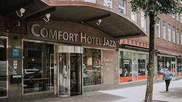 The exterior of Comfort Hotel Jazz with a modern facade, large glass windows, and a prominent entrance.