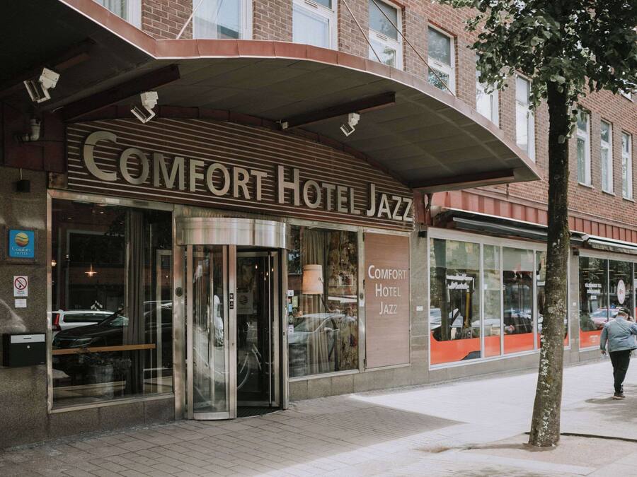 The exterior of Comfort Hotel Jazz with a modern facade, large glass windows, and a prominent entrance.