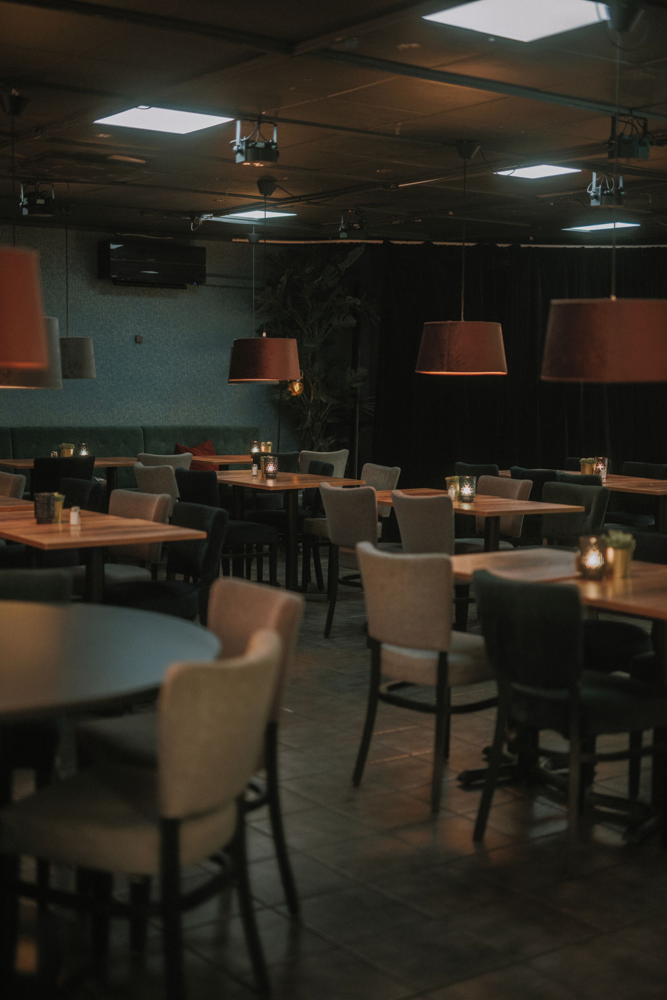 Un restaurante tenuemente iluminado con mesas y sillas dispuestas para comer.