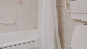 A bathroom with a bathtub, a shower curtain, and a towel rack with towels.