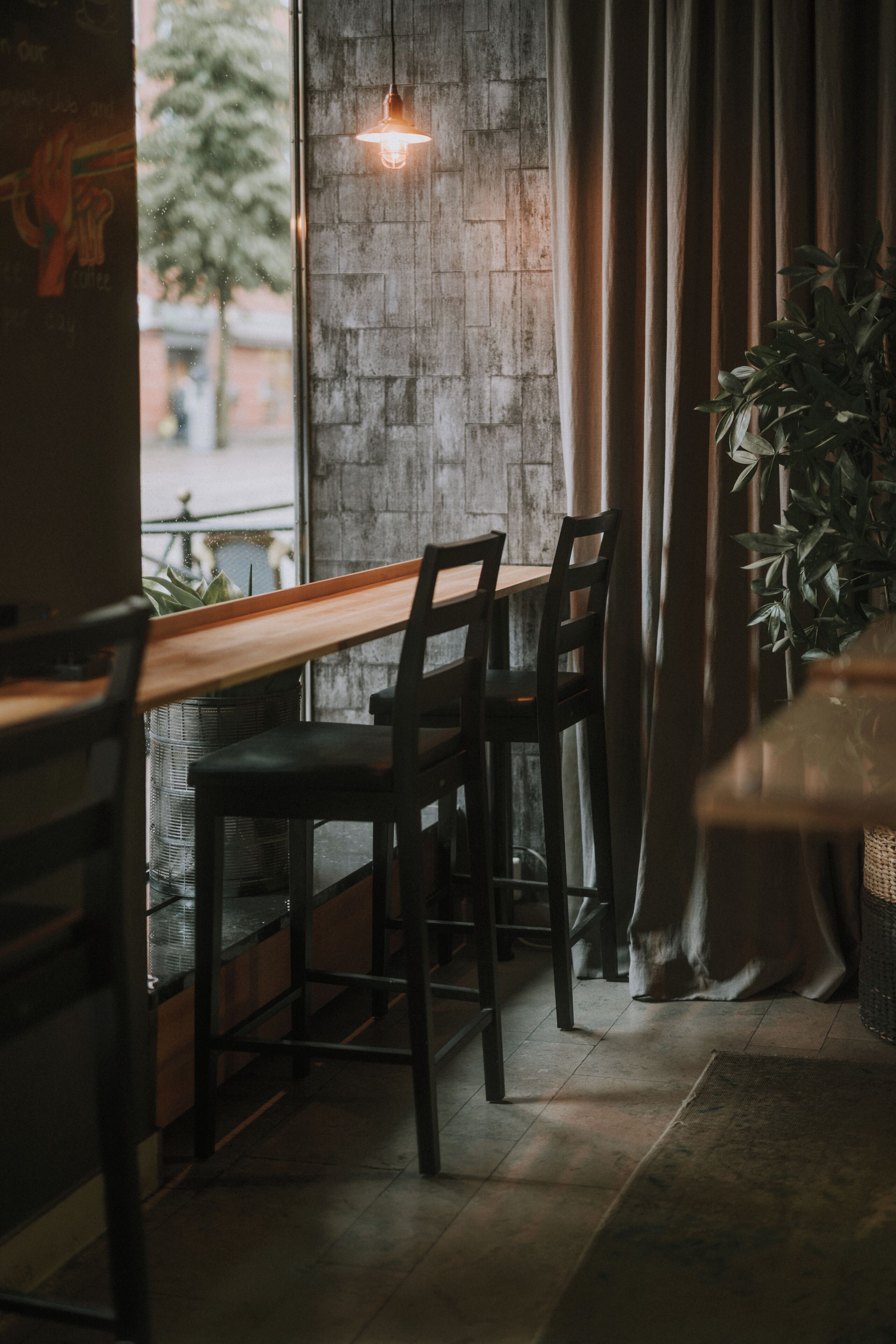 A cozy cafe with a rustic brick wall, wooden tables, and chairs.