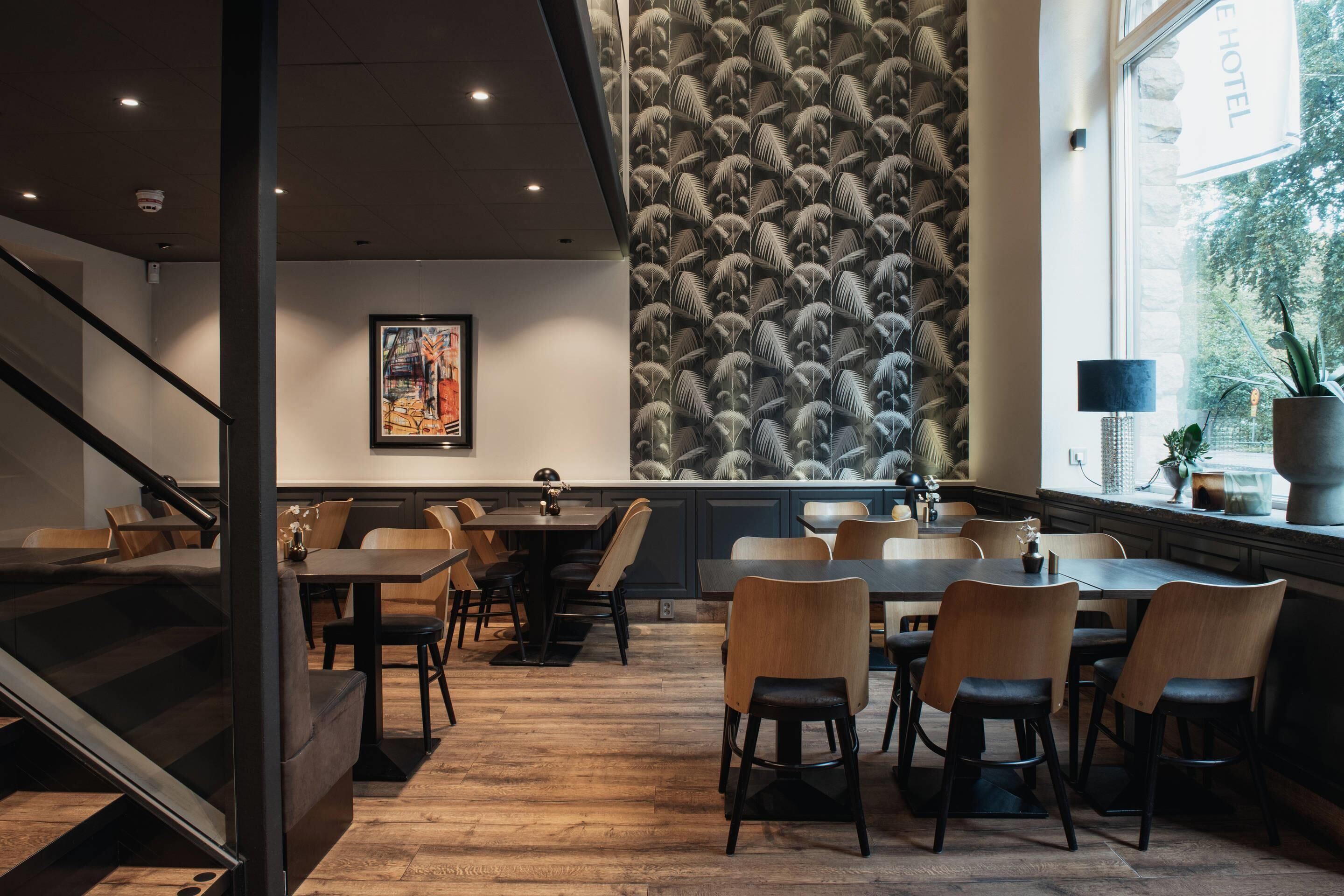 Ein modernes Hotelinterieur mit Treppe, Essbereich und Wand mit Federmotiv.