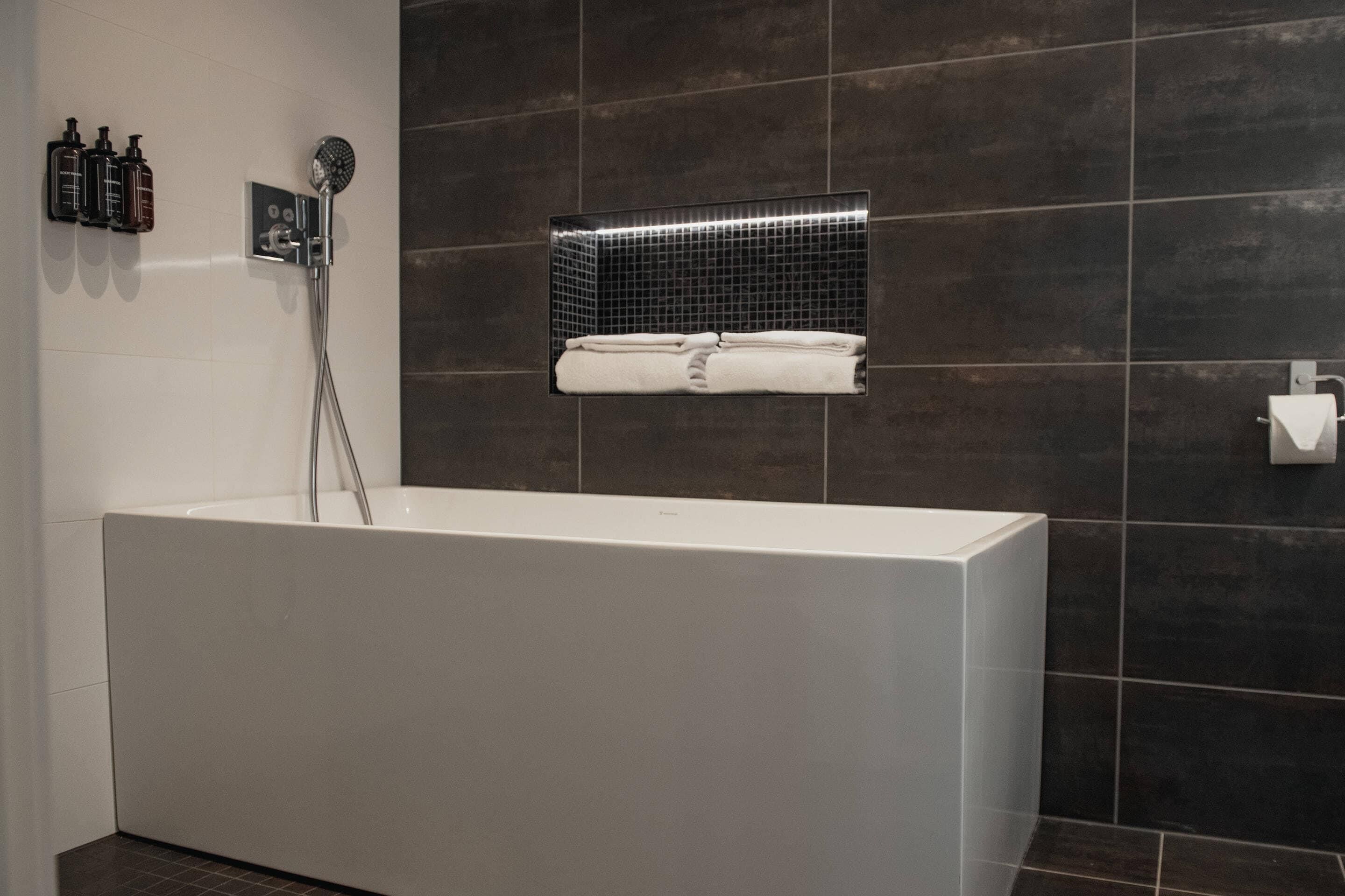 A modern bathroom with a large bathtub, a wall-mounted towel rack, and a showerhead.