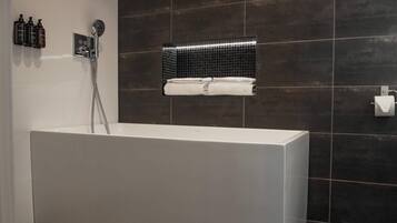 A modern bathroom with a large bathtub, a wall-mounted towel rack, and a showerhead.