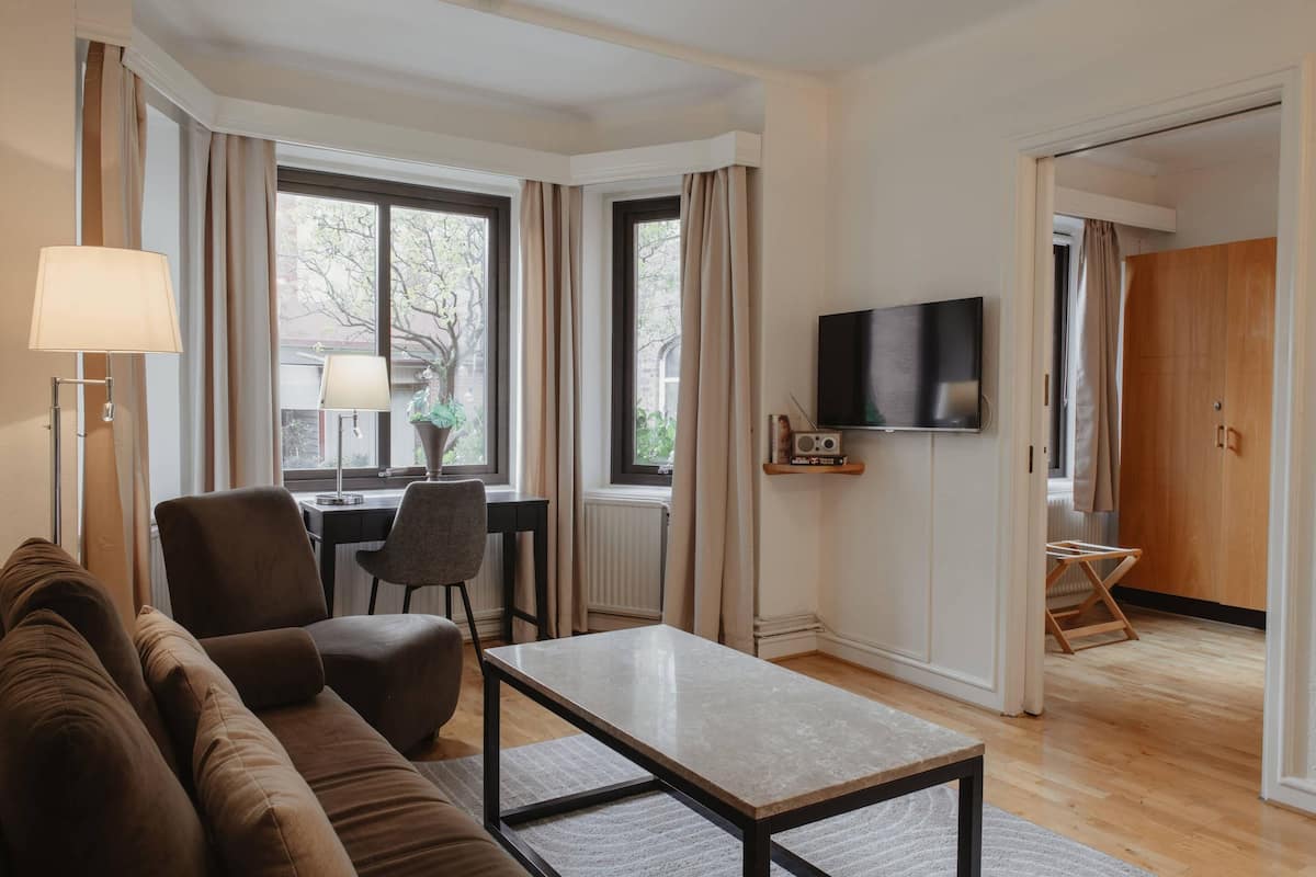 A living room with a sofa, a coffee table, a TV, and a desk with a chair.