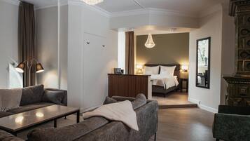 Habitació d'hotel moderna amb un sofà, una taula petita, un llit, un mirall i una làmpada penjant.