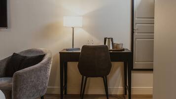 Una habitación con escritorio, silla, lámpara y puerta.