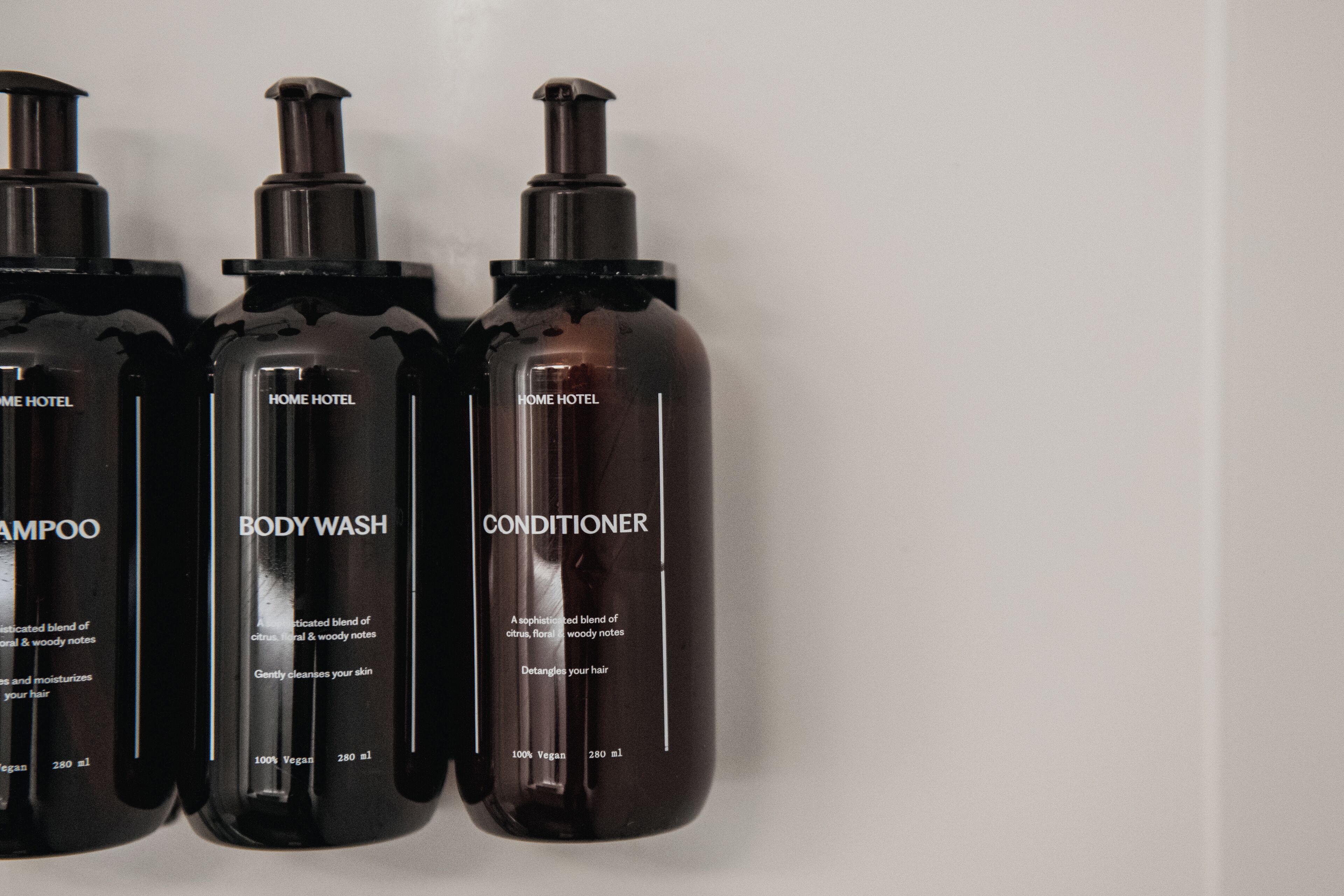 Three bottles of HOME HOTEL body wash, shampoo, and conditioner.
