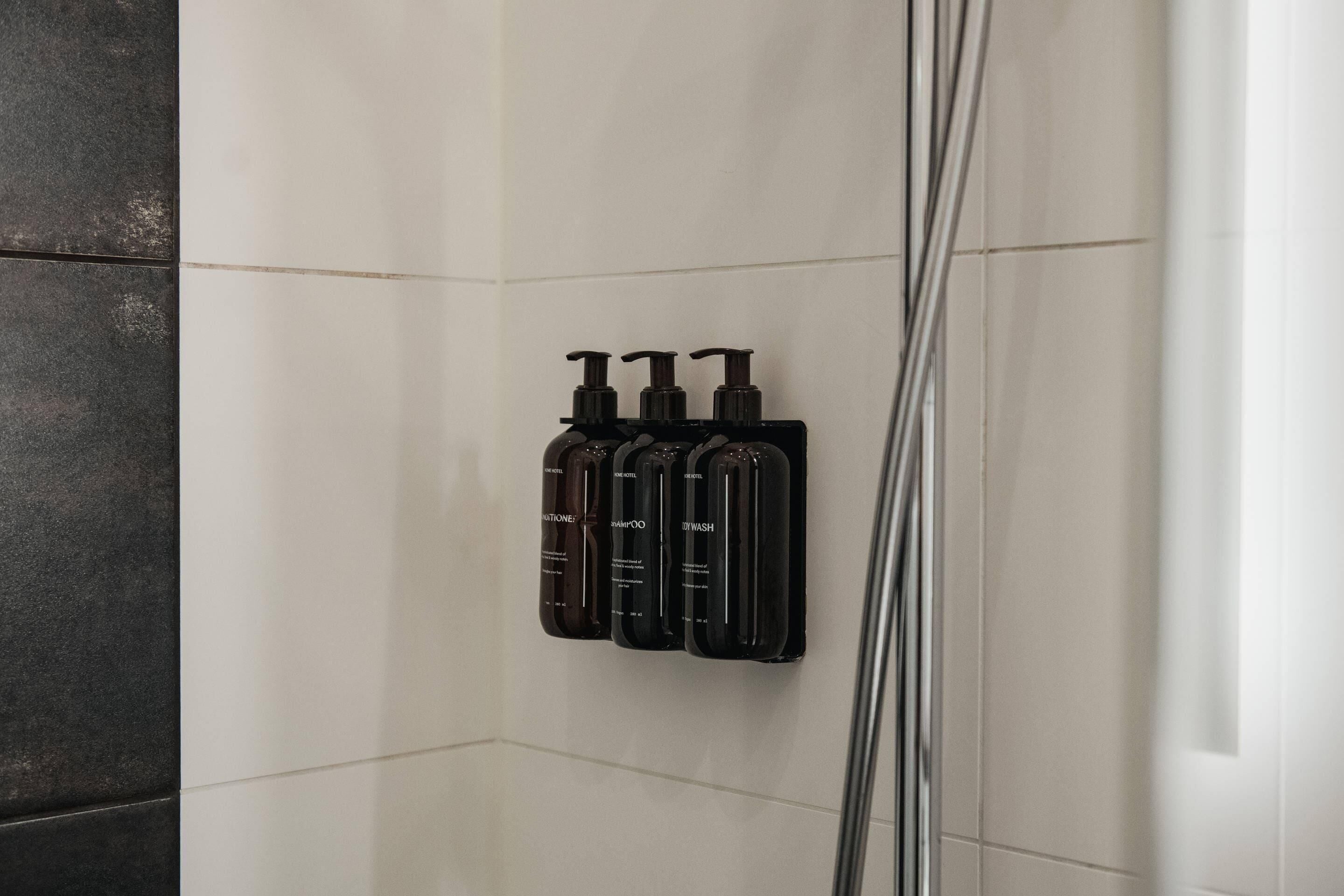 A shower area with four bottles of shampoo and conditioner.