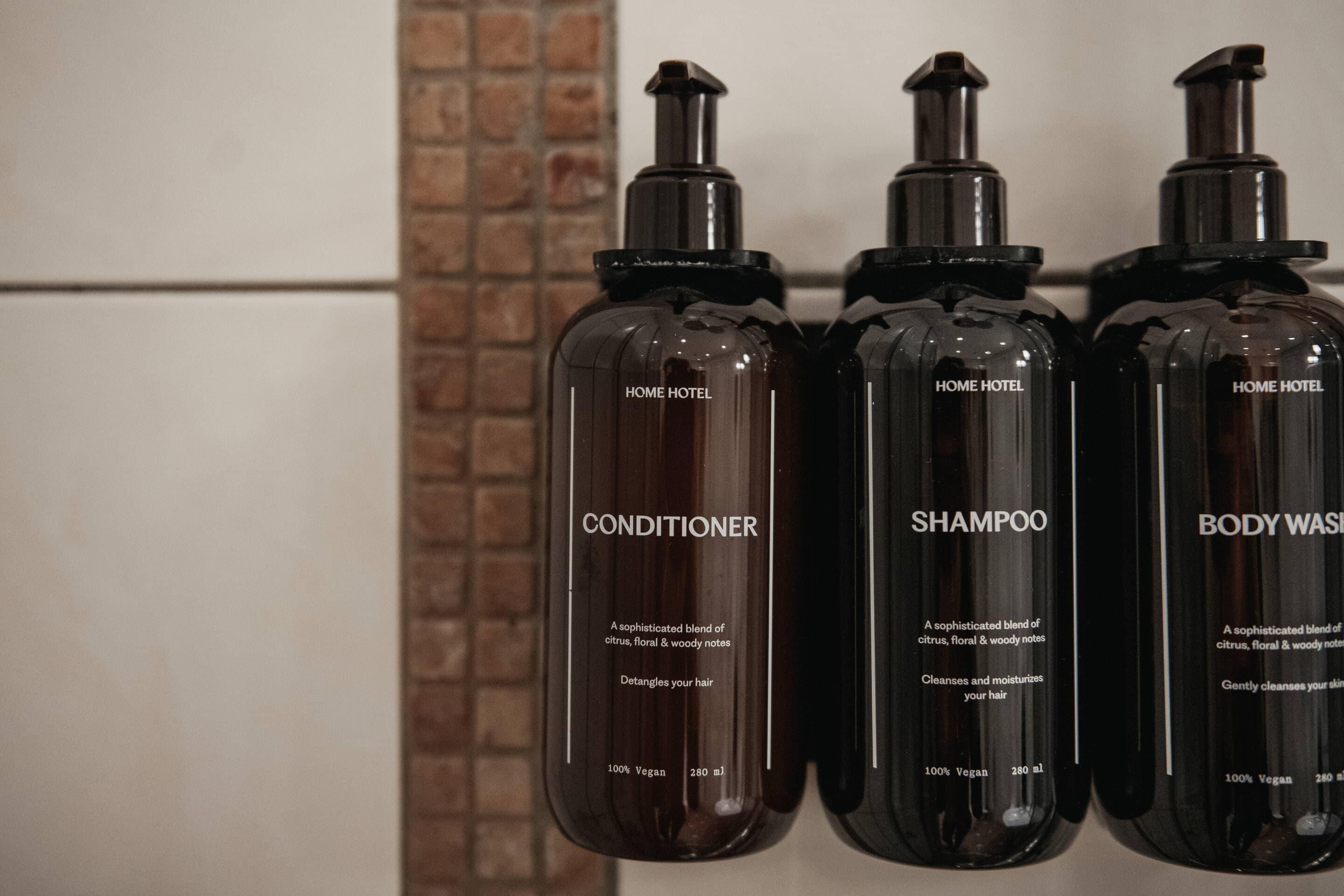 Three bottles of 'HOME HOTEL' products: conditioner, shampoo, and body wash, each labeled as 100% vegan and 280 ml.