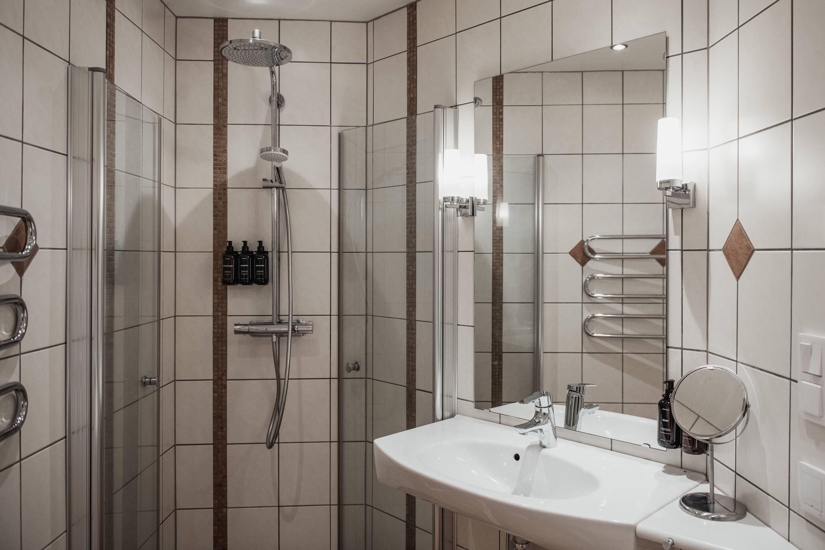 A modern bathroom with a shower, a sink, a mirror, and a towel rack.
