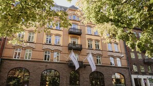 Un edificio histórico con ventanas arqueadas, un balcón central y banderas.