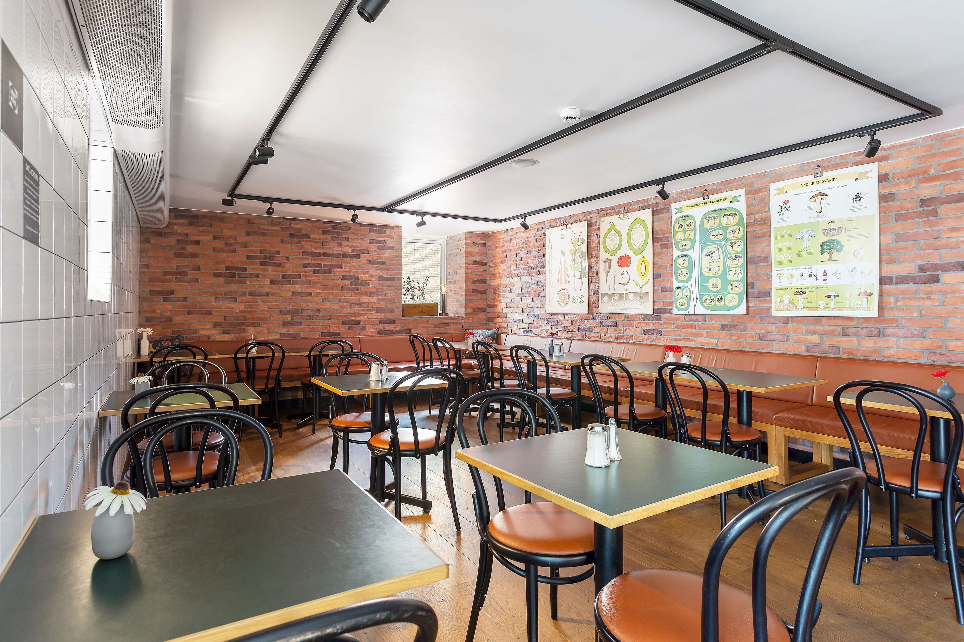 A restaurant interior with brick walls, wooden tables, and black chairs.