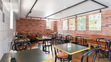A restaurant interior with brick walls, wooden tables, and black chairs.