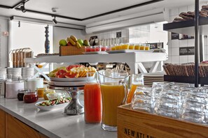 Een ontbijtbuffet met verschillende soorten fruit, sappen en gebak.