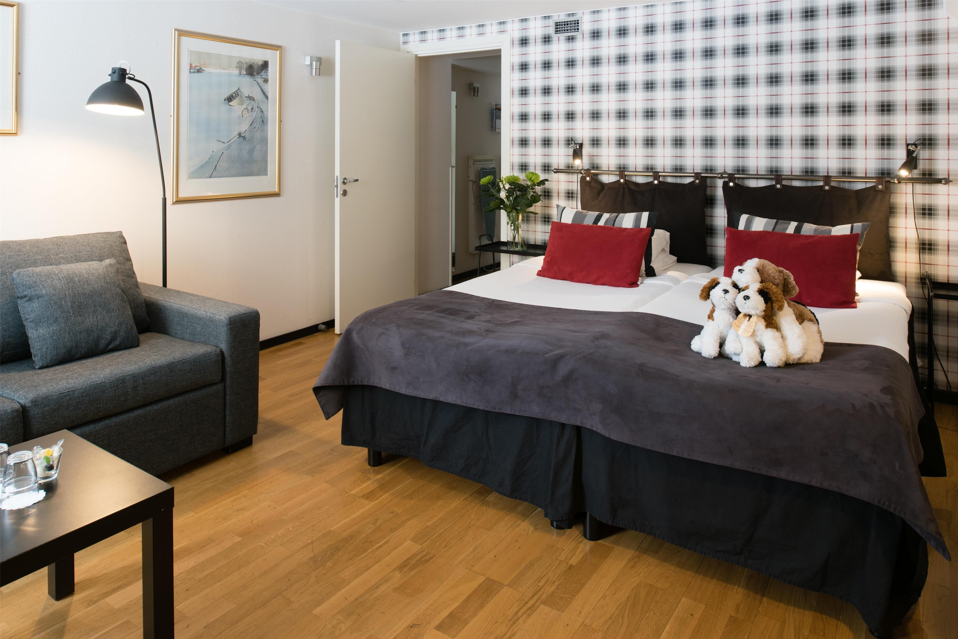 Una habitación de hotel moderna con una cama, un sofá, una mesa y un cuadro en la pared.