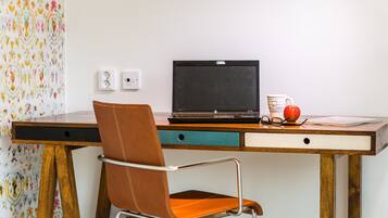 A desk with a laptop, a chair, a mug, and an apple.