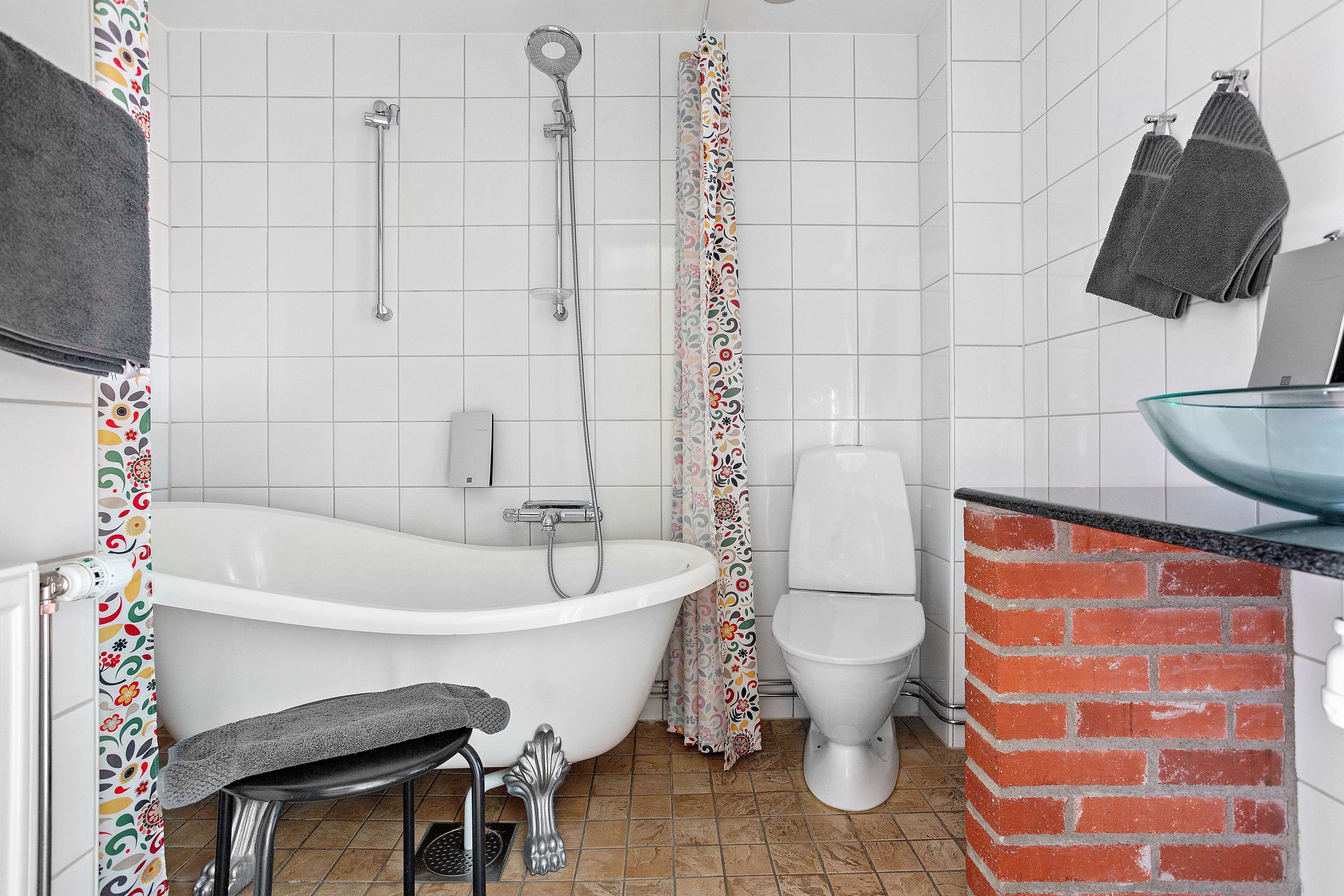 Une salle de bain avec une baignoire blanche, des toilettes et un lavabo doté d’un receveur en verre.