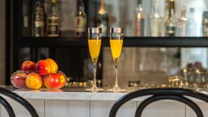 Un coin bar avec un présentoir en verre rempli de fruits et deux verres de jus d’orange.